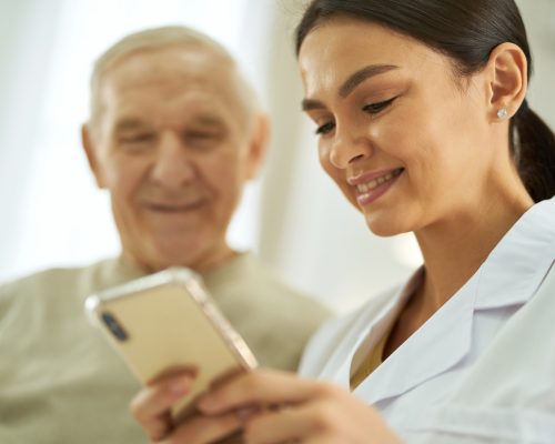 Smiling nurse and senior citizen looking at smartphone screen